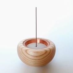 a wooden candle holder with a single stick sticking out of the top, on a white surface