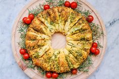 a bundt cake with cherry tomatoes and rosemary on the side, sitting on a wooden platter