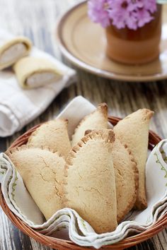 some cookies are in a basket on a table next to a potted plant and napkins