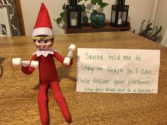 an elf is sitting next to a sign on a table