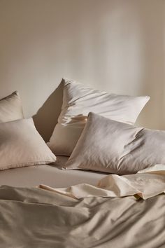 a bed with white sheets and pillows on it