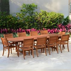 a large wooden table and chairs in front of some bushes