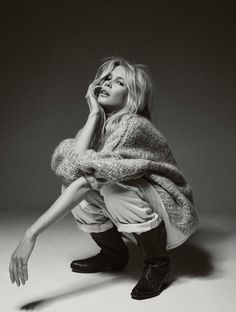 a black and white photo of a woman sitting on the ground with her hand to her face