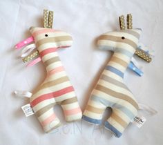 two stuffed giraffes sitting next to each other on top of a white sheet