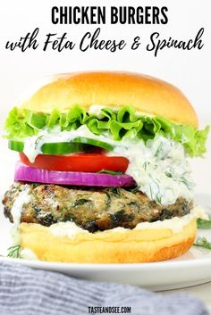 chicken burgers with feta cheese and spinach on a white plate next to a blue towel