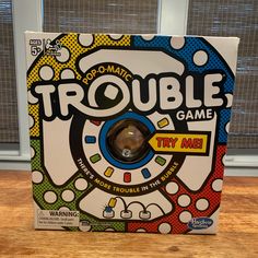 the trouble game is in its box on top of a wooden table next to a window