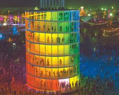 an aerial view of a building lit up at night with people walking around the outside