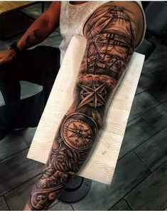 a man's arm with a ship and compass tattoo on it