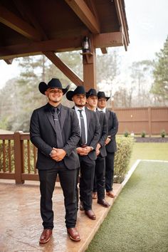 a group of men in suits and hats standing next to each other on a porch