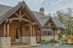 a large wooden house with stone pillars and windows