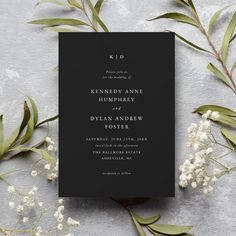 a black and white wedding card with greenery on the side, next to it