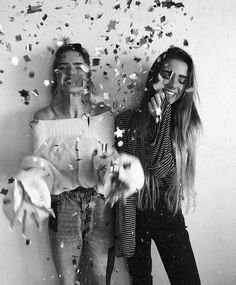 two young women standing next to each other with confetti in front of them