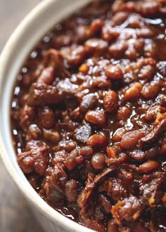 a white bowl filled with chili beans on top of a wooden table