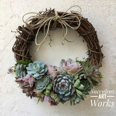 a wreath with succulents is hanging on the side of a white wall