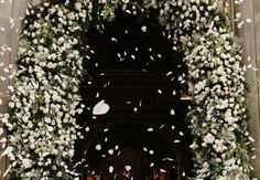 an archway decorated with white flowers and petals