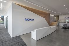 an office lobby with white walls and blue nokia logo on the wall next to stairs