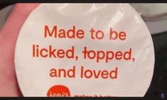 a person holding up a white plate with an orange message on the side that says made to be licked, topped, and loved