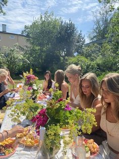 a group of women sitting around a table eating food