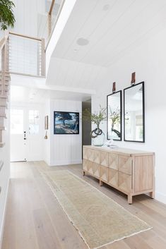 a white room with two mirrors and a rug on the floor in front of it