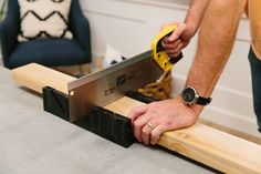 a man is using a saw to cut a piece of wood with a large pair of scissors