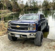 a blue truck parked on the side of a river