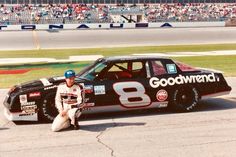 a man sitting on the ground next to a race car