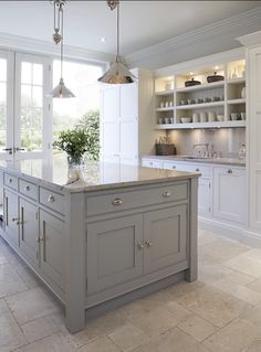 a kitchen with white cabinets and an island in the middle of the room is lit by two pendant lights