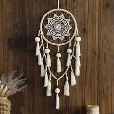 a white dream catcher hanging on a wooden wall