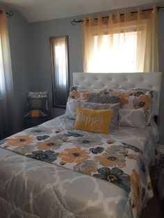 a bed with yellow and gray pillows in a bedroom next to two window sills