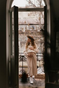 a woman standing in front of an open door with her hand on her hip and looking at the camera