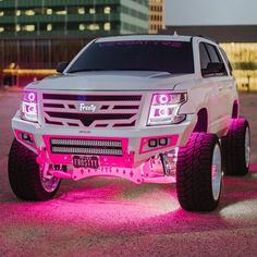 a white truck with pink leds parked in a parking lot