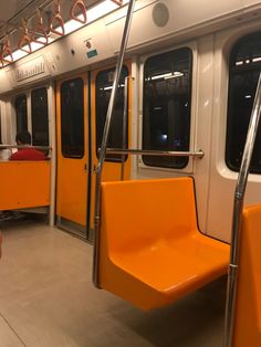 the inside of a subway car with orange seats and railings on both sides,