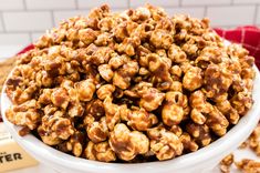 a white bowl filled with caramel popcorn on top of a table next to a book