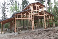 a house under construction in the woods with lots of wood framing on it's sides