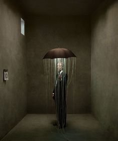 a man standing in a room holding an umbrella over his head with strings attached to it