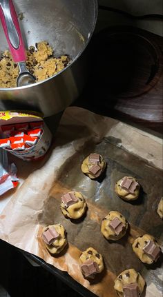 some cookies are sitting on a cookie sheet and next to a pan with chocolate chips