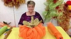 a woman sitting at a table surrounded by fake flowers and carrots in front of her