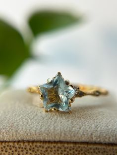 a close up of a ring on top of a box with a plant in the background