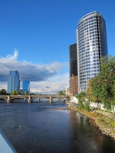 a river running through a city with tall buildings on either side and a bridge crossing over it