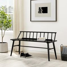 a black bench sitting in front of a window next to a potted green plant