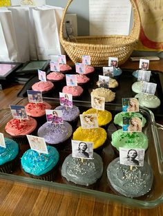 there are many cupcakes on the table with pictures and cards attached to them