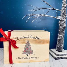 a wooden box with a christmas tree on it and a red ribbon tied around it