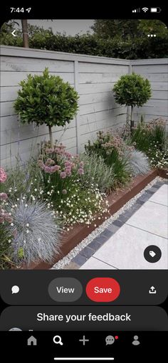 an image of a garden with flowers and plants on the side of a fenced in area