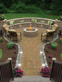 an outdoor fire pit surrounded by chairs and flowers