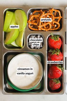 a lunch box with apples, pretzels, chocolate chips, cinnamon in vanilla yogurt and strawberries