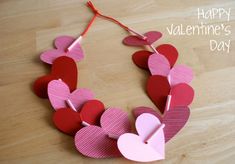 a paper heart necklace is shown on a wooden surface with the words happy valentine's day written below it