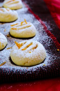 some cookies are sitting on a red and black towel with orange zest sprinkles