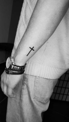 a man with a cross tattoo on his wrist