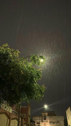 the street light is shining brightly in the dark sky above some trees and buildings at night