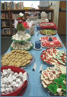 a long table covered in lots of different types of cookies and pastries on plates